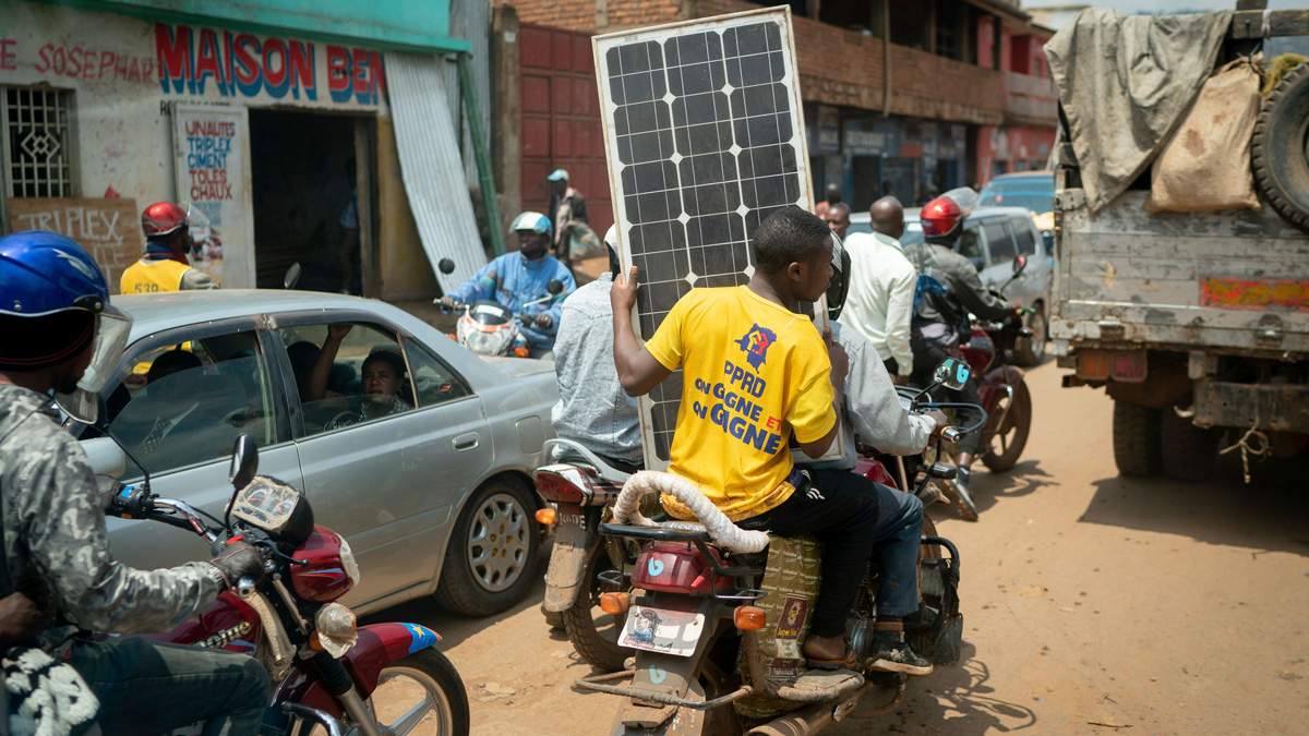 A motorcyclist transports a solar panel.