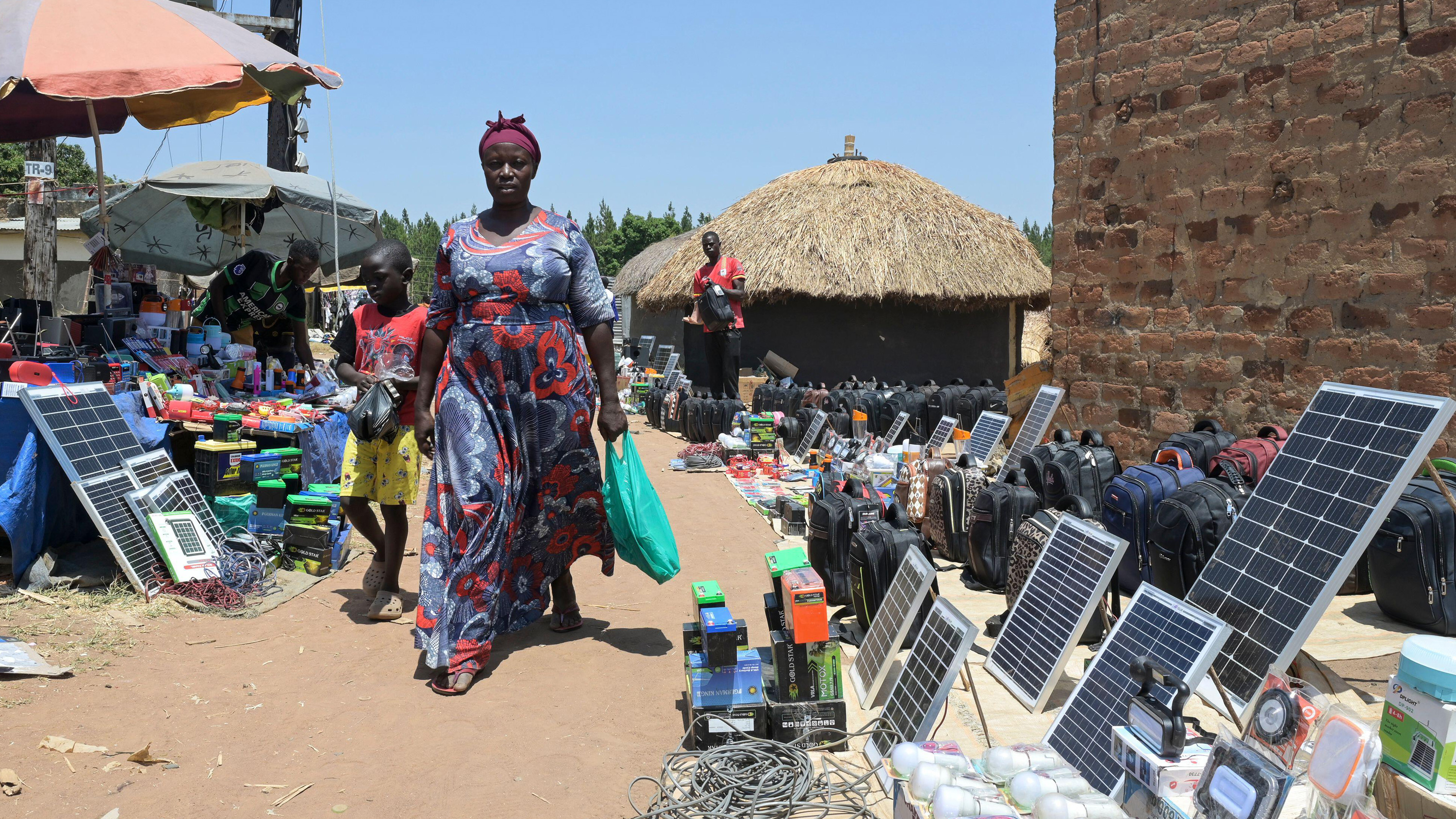Women walks through a market with solar panels lining the street