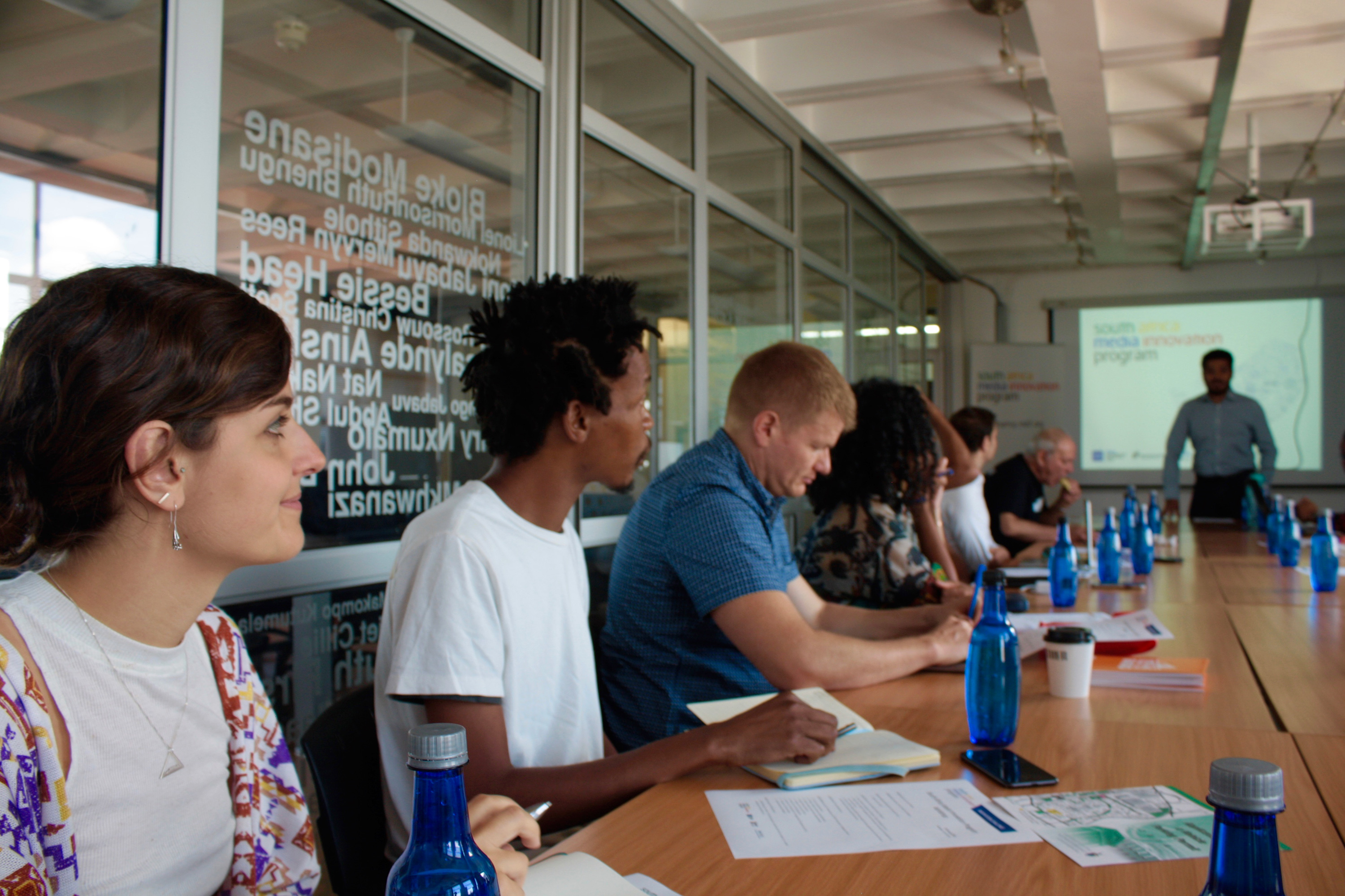 A group of people at desks watching a presentation