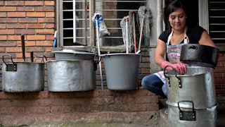 A woman washes a stack of aluminum pots