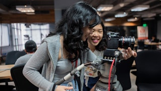 Two young women setting up a professional camera on a tripod