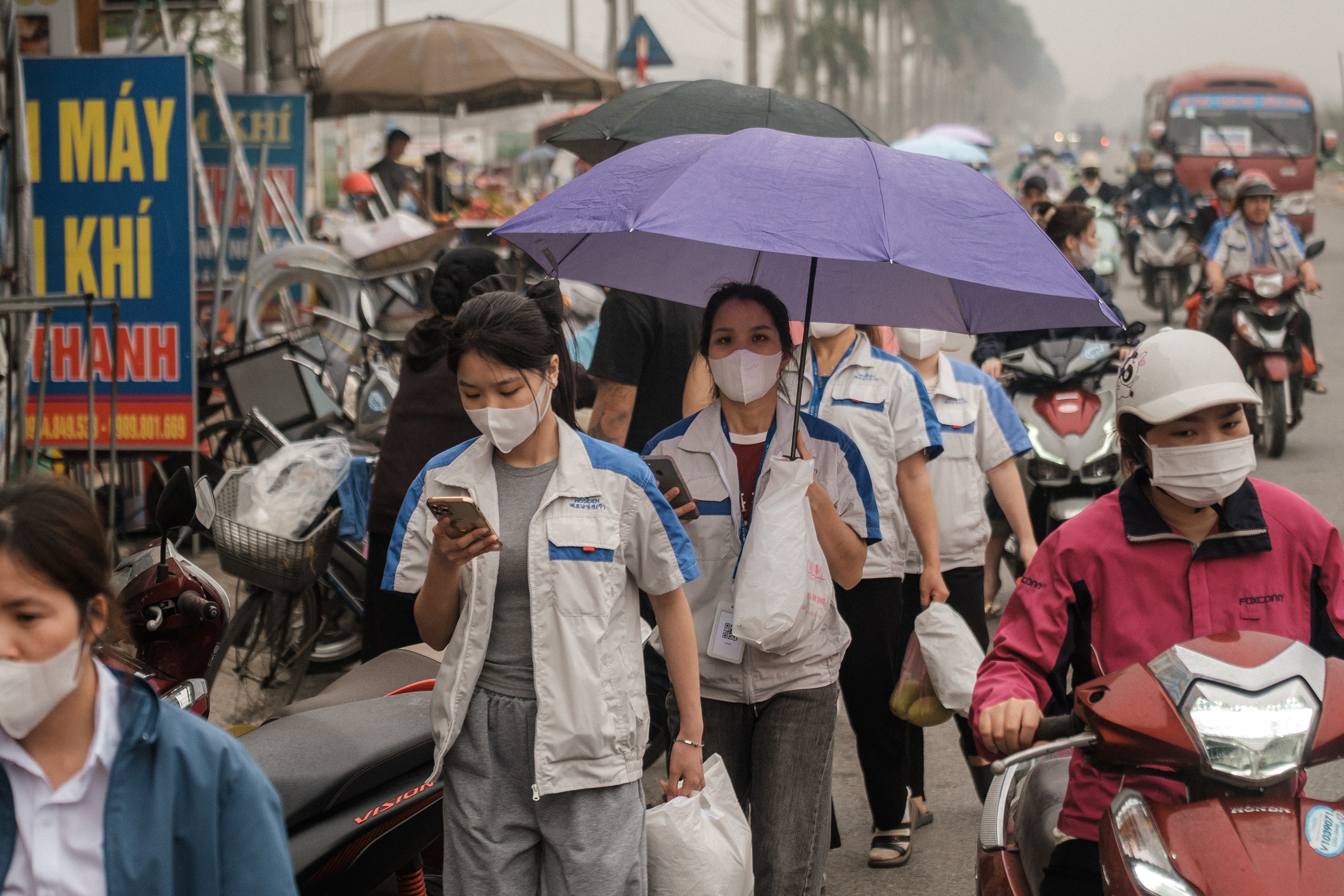 People walk on a crowded city street looking at their phones