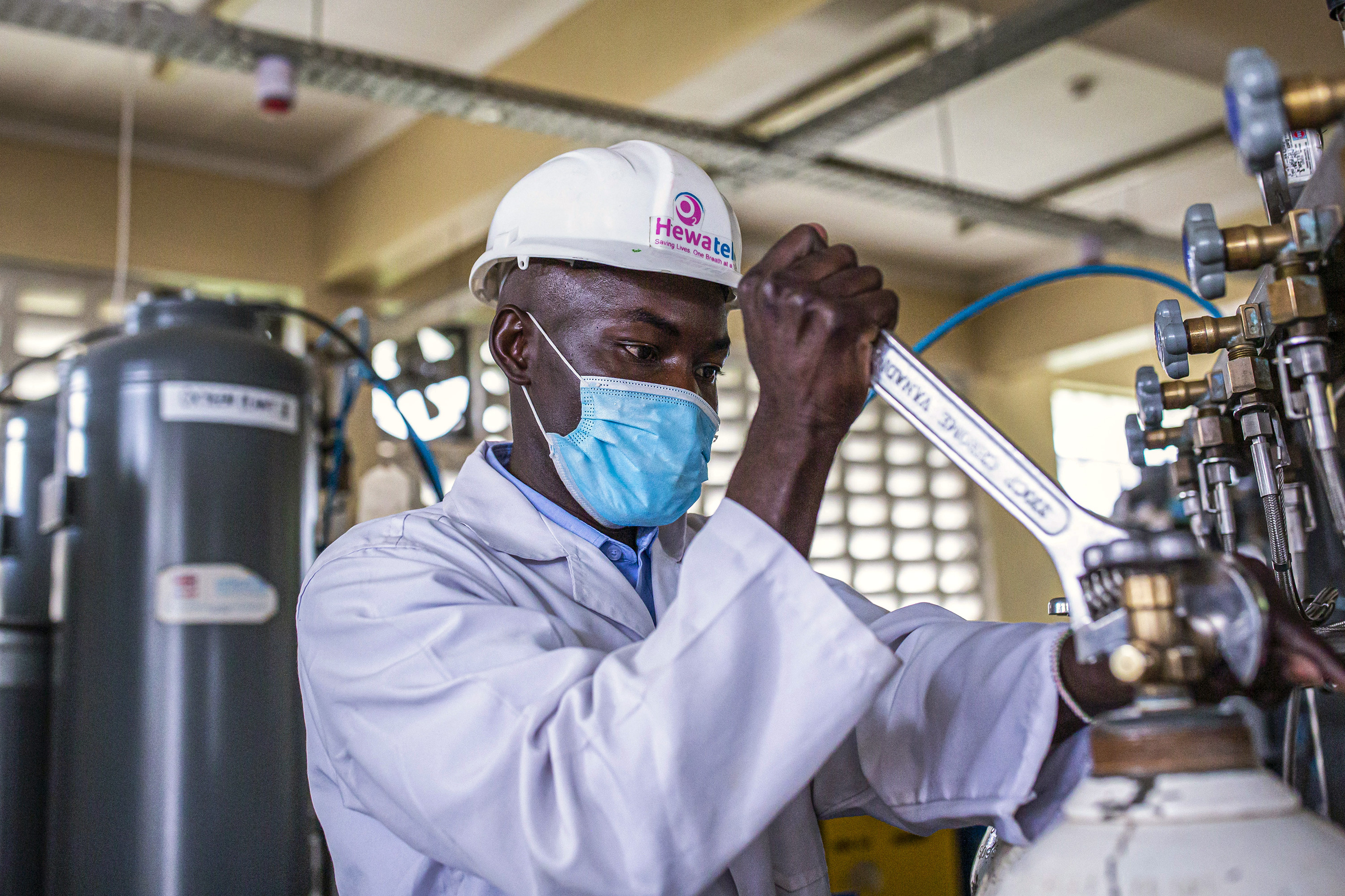 A man wearing a helmet using a wrench.