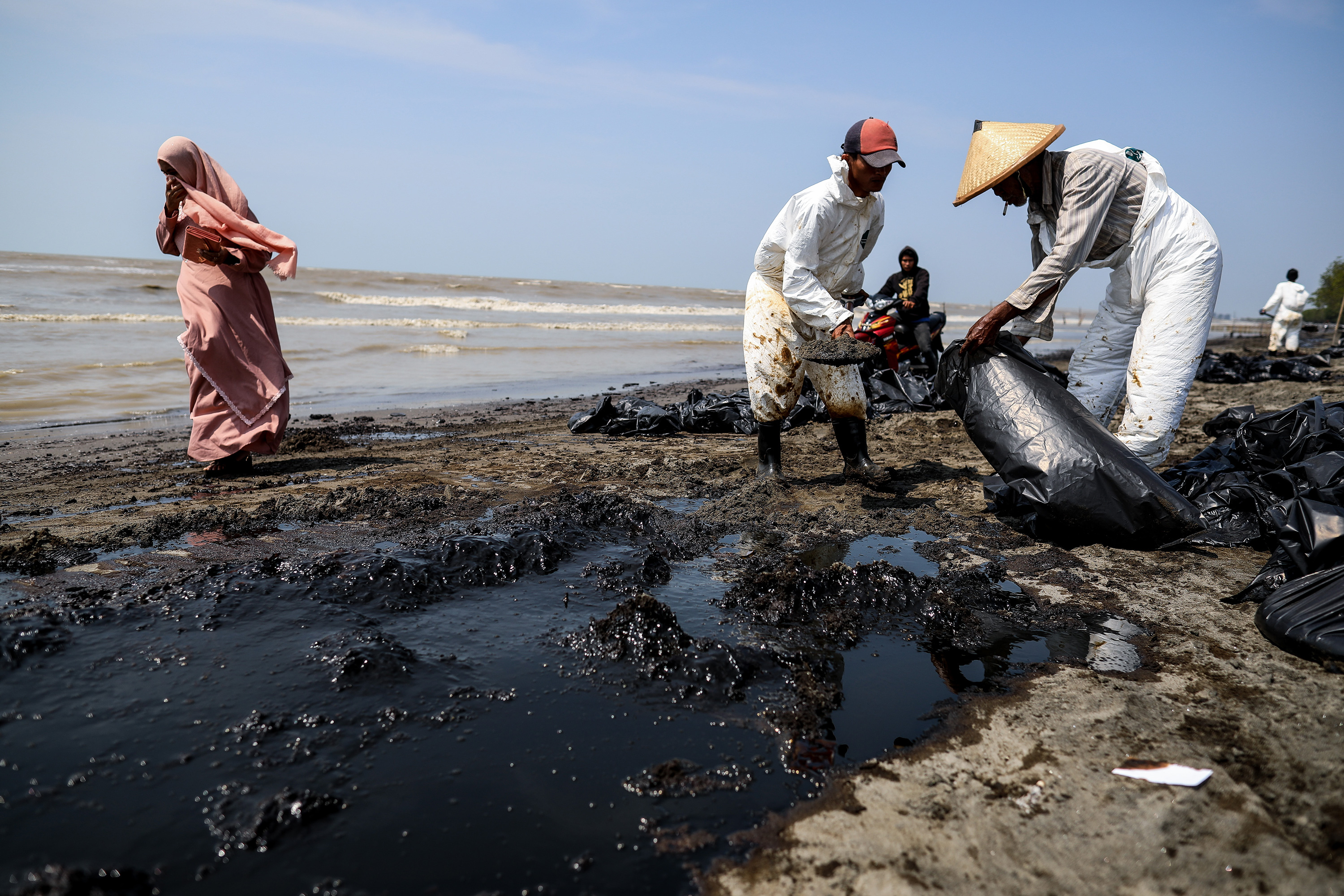 Workers clean up oil spilled on a beach