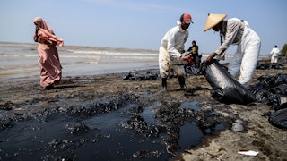 Workers clean up oil spilled on a beach