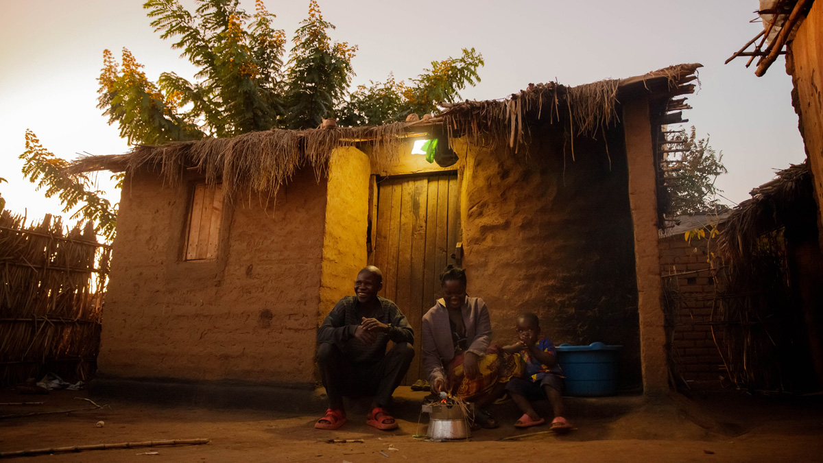 Two adults and a child sitting outside near a front door of a home