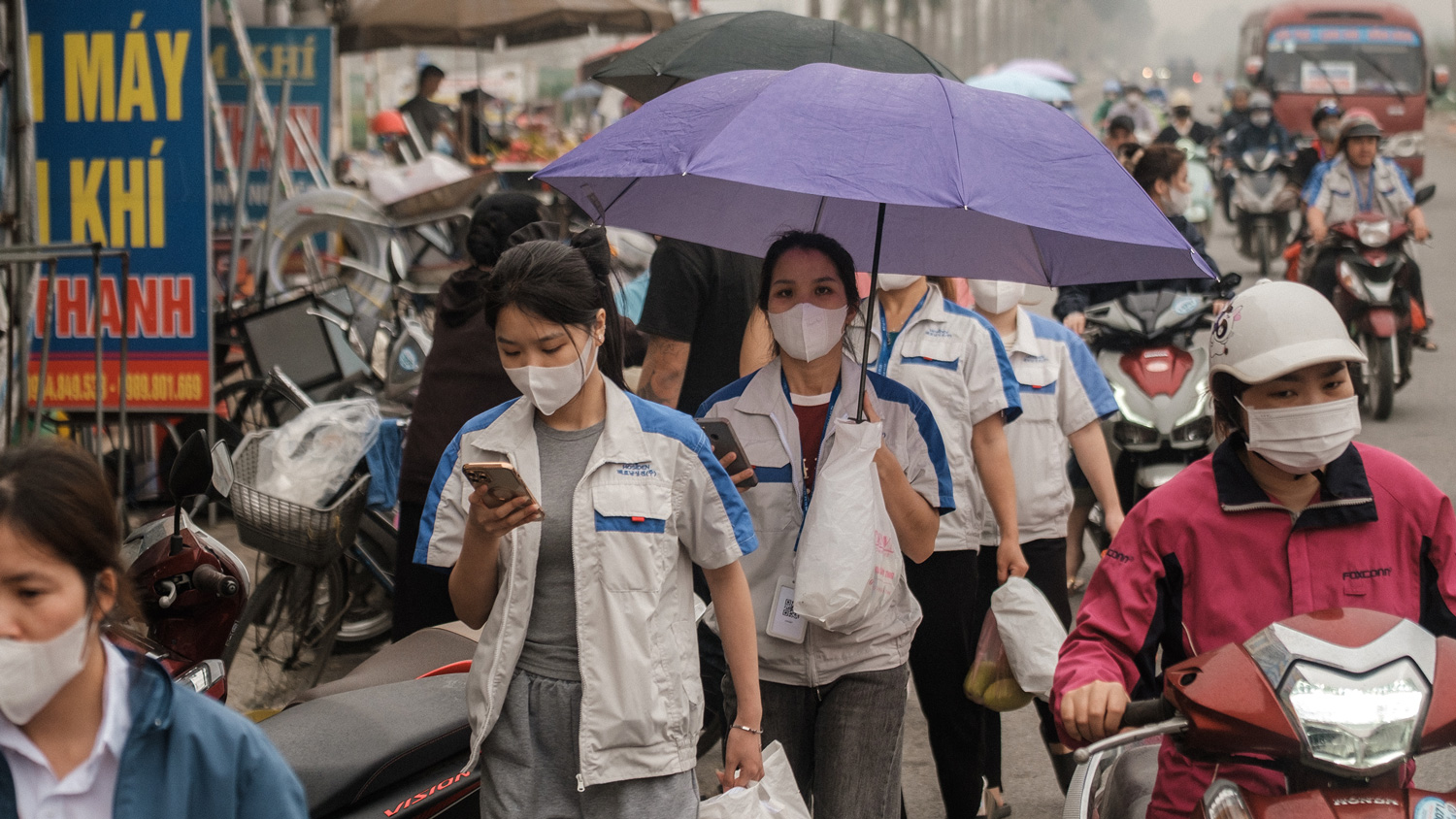 People walk on a crowded city street looking at their phones