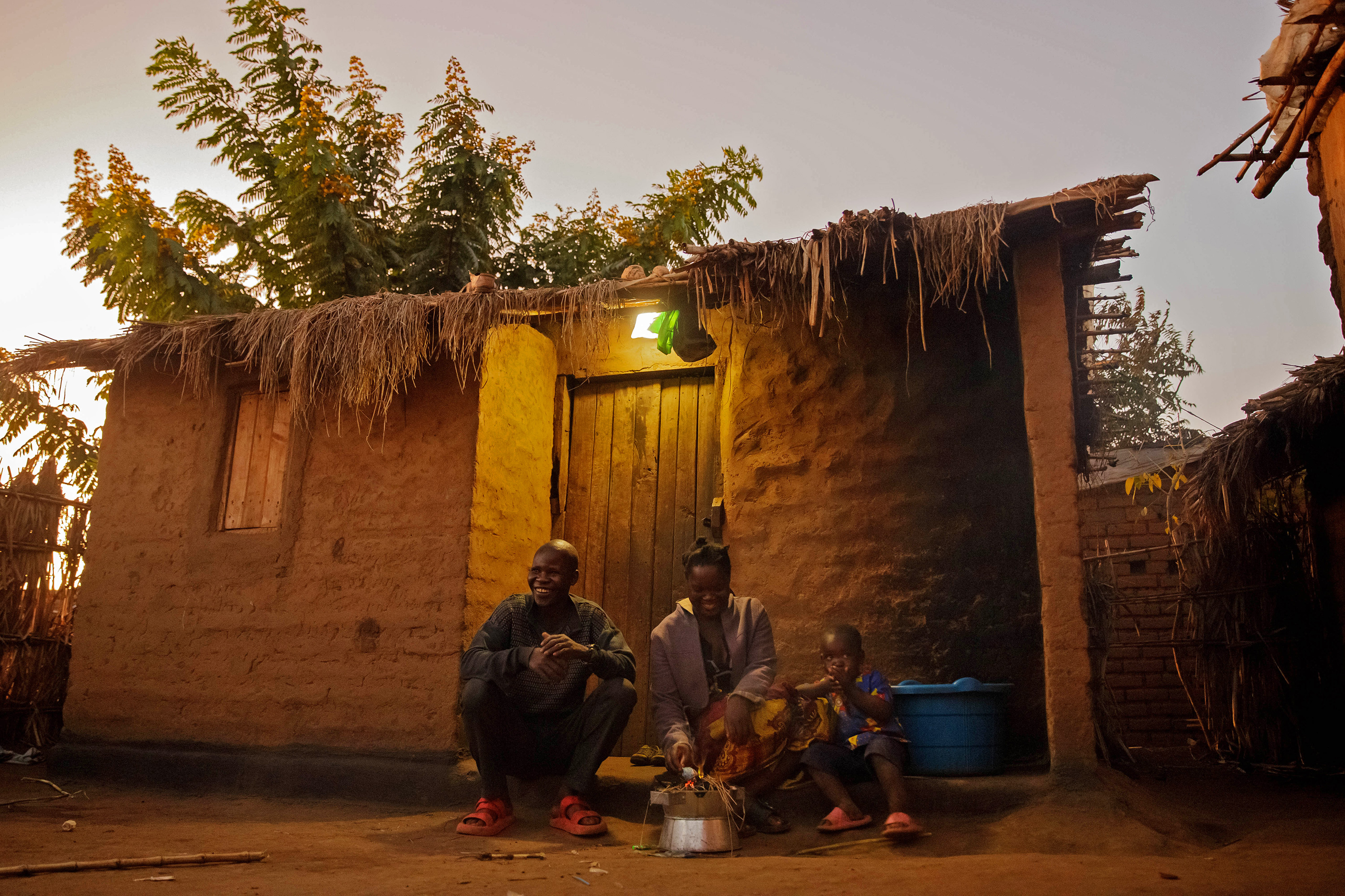 Two adults and a child sitting outside near the front door of a home