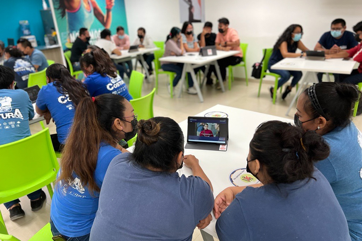 Groups of people sitting at desks looking at tablets