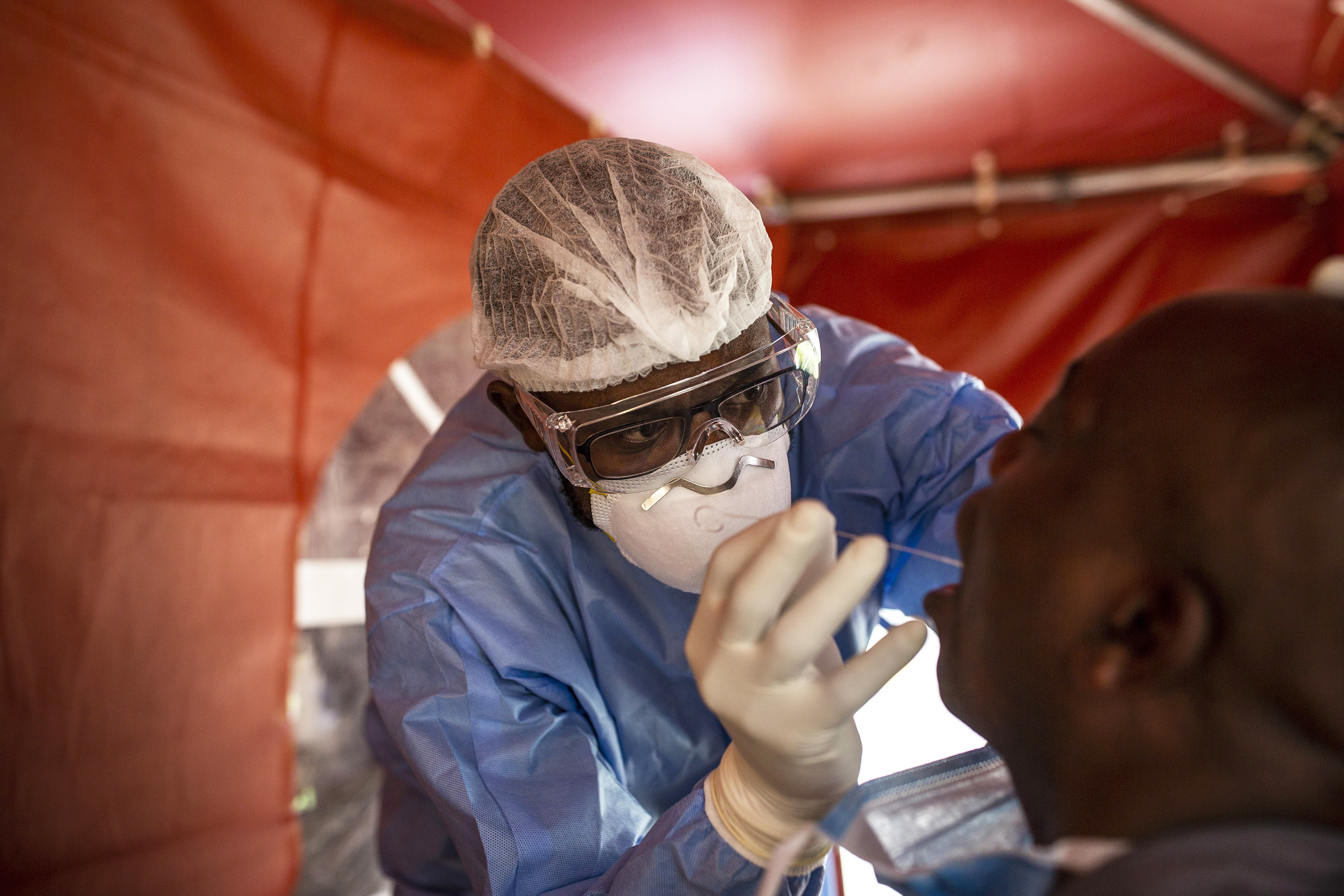 A health worker wearing full personal protection equipment taking a swab from a patient