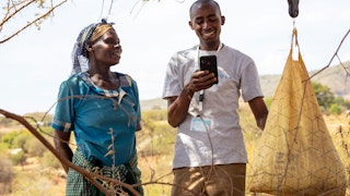 A man holding a phone standing next to a woman in a field
