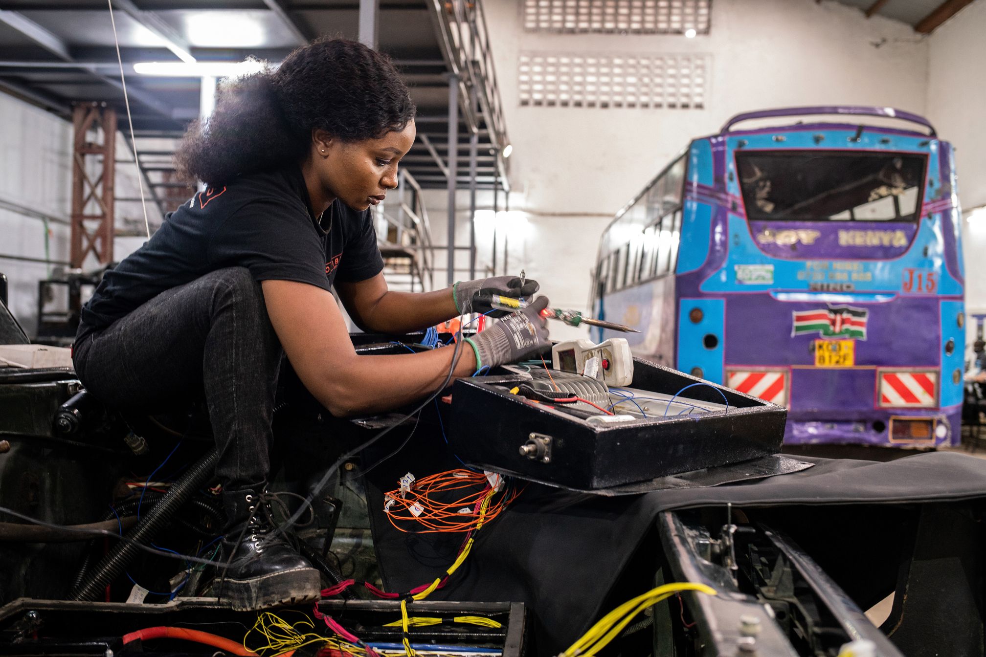 A woman works on a battery in a workshop